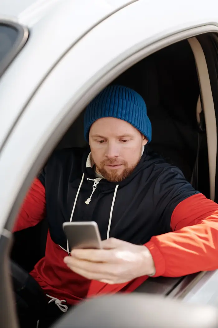 A tradesman reading his phone in his van